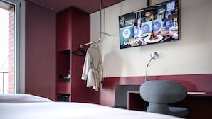 Une chambre d’hôtel équipée d’un lit, d’un téléviseur fixé au mur, d’un bureau et d’une chaise.