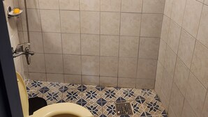 Ein kleines Badezimmer mit Dusche, Toilette und Fliesenboden.