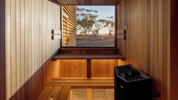A sauna room with wooden walls, a bench, and a sauna heater.