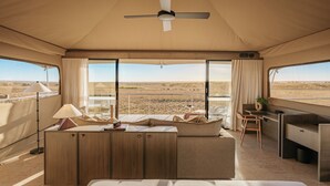 A tented room with a bed, a desk, and a view of the landscape. - Monarto Safari Resort (Monarto)