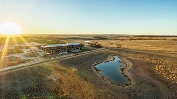 An aerial view of a building with a parking lot and a small pond.