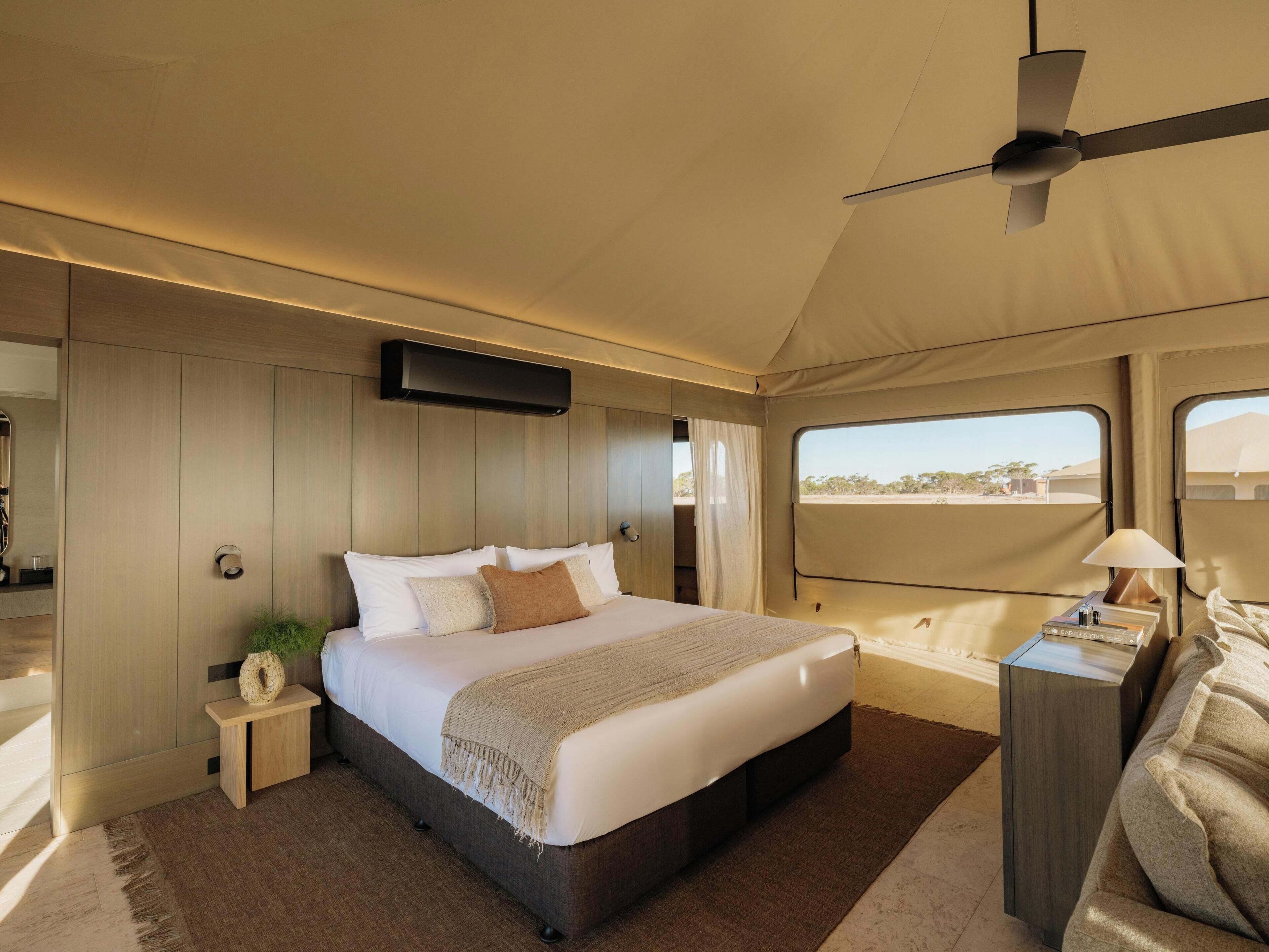 A bedroom with a bed, bedside table, lamp, and a ceiling fan.