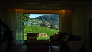 A living room with a large window offering a view of a green landscape and hills. - Luxury Coastal Vineyard Escape | The Canopy | Crooked River Estate (Gerringong)