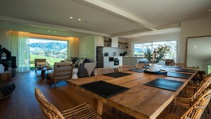 A spacious living area with a large wooden dining table, wicker chairs, and a view of the outdoors. - Luxury Coastal Vineyard Escape | The Canopy | Crooked River Estate (Gerringong)