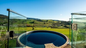 A glass-enclosed infinity pool with a clear view of a lush green landscape and distant hills. - Luxury Coastal Vineyard Escape | Flame Vista | Crooked River Estate (Gerringong)