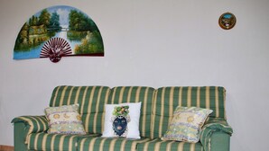 A green sofa with striped cushions and a decorative pillow with a floral design. - Villa La Perla (Marsala)