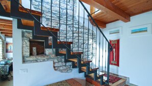 A staircase with a stone wall and wooden steps, leading to a lower level.