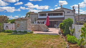 A two-story house with a stone facade, a red umbrella, and a well-maintained garden. - Charming home with pool in Barbariga (Peroj)