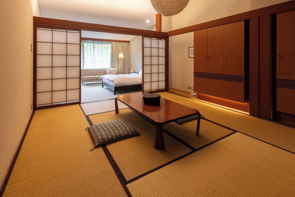 Um quarto em estilo japonês tradicional, com tatames, uma mesa de madeira baixa e portas deslizantes.