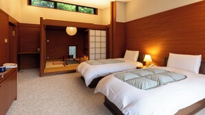 A hotel room with two beds, wooden headboards, a traditional Japanese sliding door, and a small desk with a lamp. - Caesar Gora Club Hakone (Hakone)