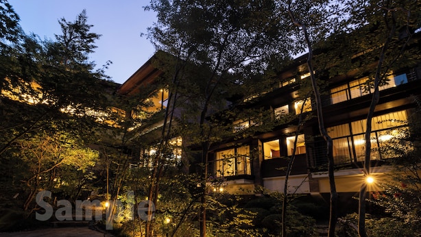 A multi-story building with illuminated windows and a garden area with steps leading up to the entrance. - Caesar Gora Club Hakone (Hakone)