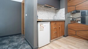 A compact kitchen with a built-in dishwasher, wooden cabinets, and a marble backsplash. - 216 F&B Suites (Istanbul)