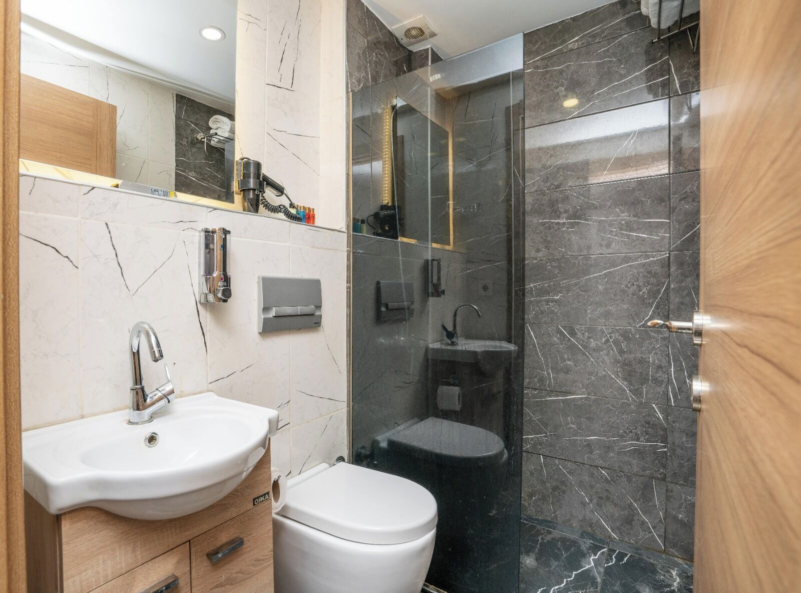 Un baño moderno con lavamanos blanco, inodoro y ducha con mampara de vidrio.