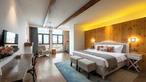 A modern hotel room with a large bed, a dining area, and a view of the city. - Shanshui S Hotel  (Wuhan)
