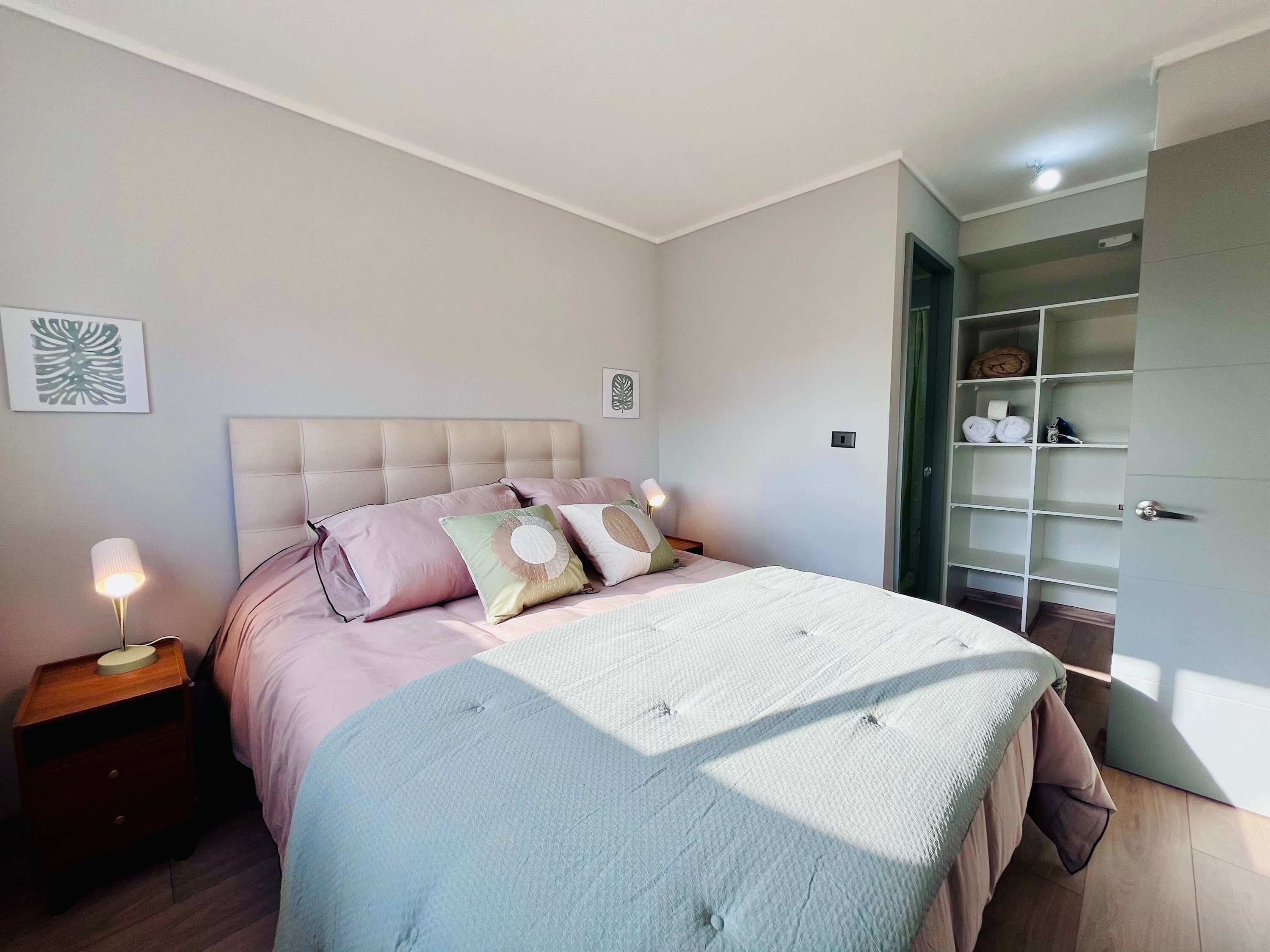 A bedroom with a bed, bedside tables, and a wardrobe.