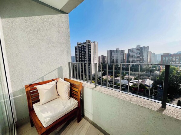 A balcony with a wooden bench and a view of a cityscape. - 1BR La Florida - Free Parking, Pool & Metro (La Florida)