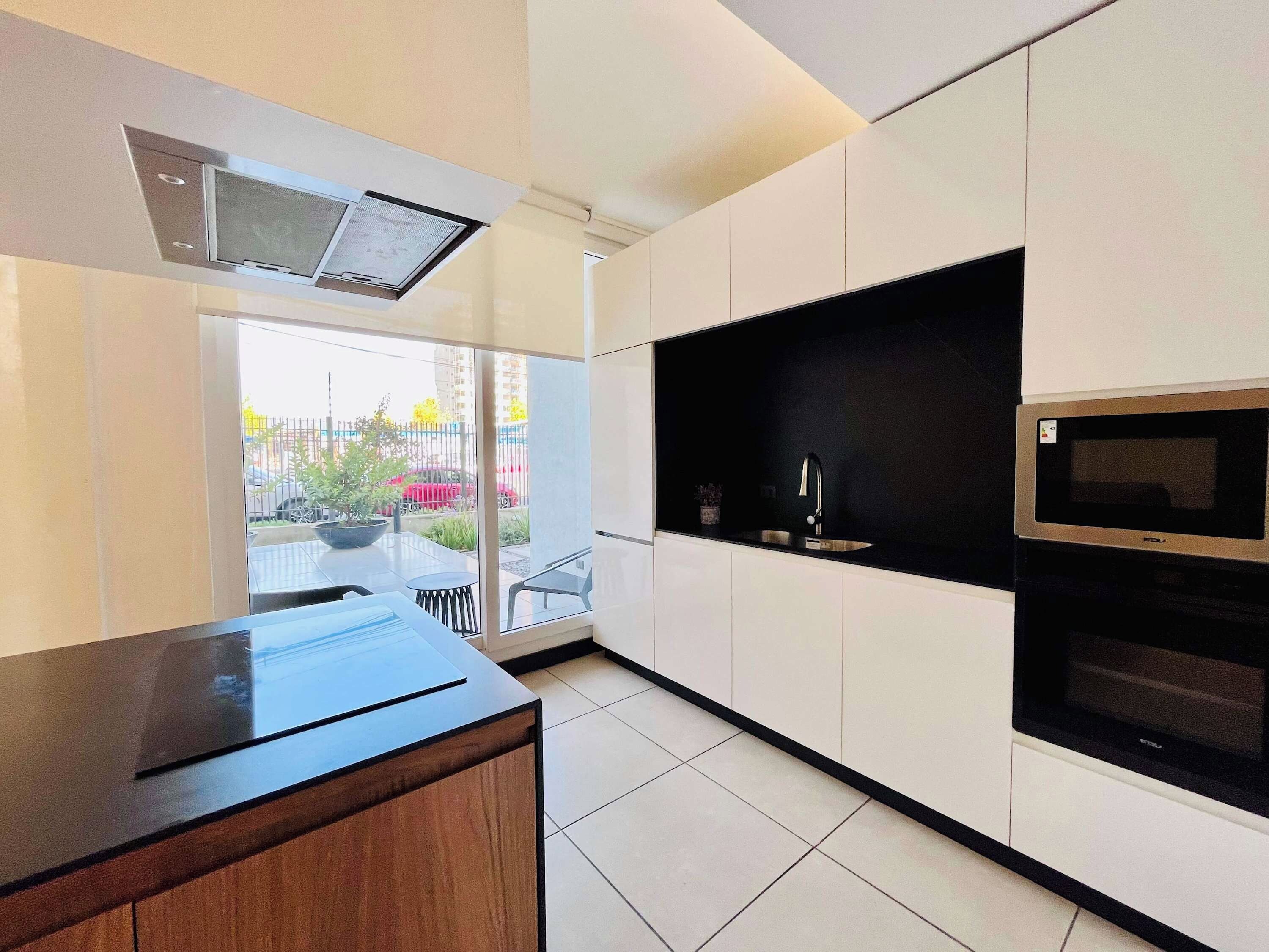 Una cocina moderna con microondas integrado, un lavamanos y una ventana con vistas a un jardín.