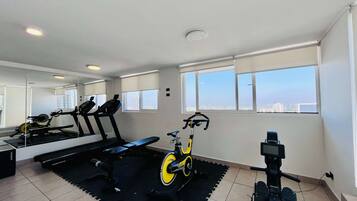A gym with exercise equipment, large windows, and a city view.