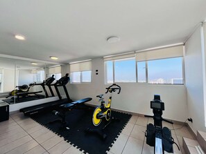 A gym with exercise equipment, large windows, and a city view. - 1BR La Florida - Free Parking, Pool & Metro (La Florida)
