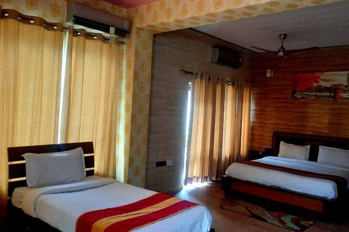 A room with two beds, a wooden headboard, a ceiling fan, and a painting on the wall.