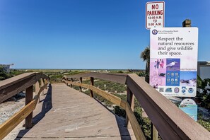 A wooden boardwalk leading to a beach with a 'No Parking' sign and a signboard about respecting natural resources. - Updated 3-bedroom, 2 bath coastal cottage across from the beach UNIT A (Fernandina Beach)