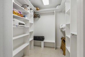 A walk-in closet with white shelving, a bench, and a hanging rack. - Updated 3-bedroom, 2 bath coastal cottage across from the beach UNIT A (Fernandina Beach)