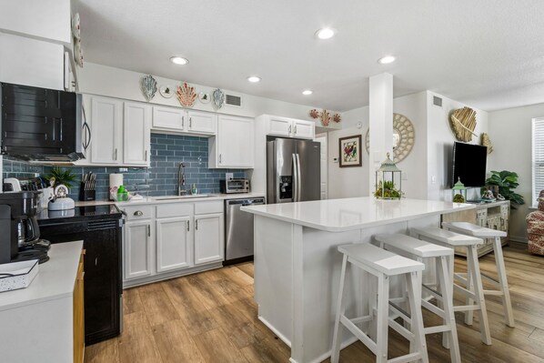 A modern kitchen with white cabinets, stainless steel appliances, and a central island with stools.