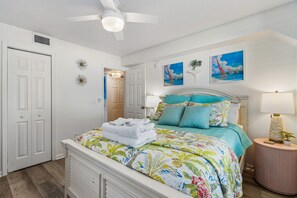 A bedroom with a bed, a nightstand, a lamp, and a ceiling fan.