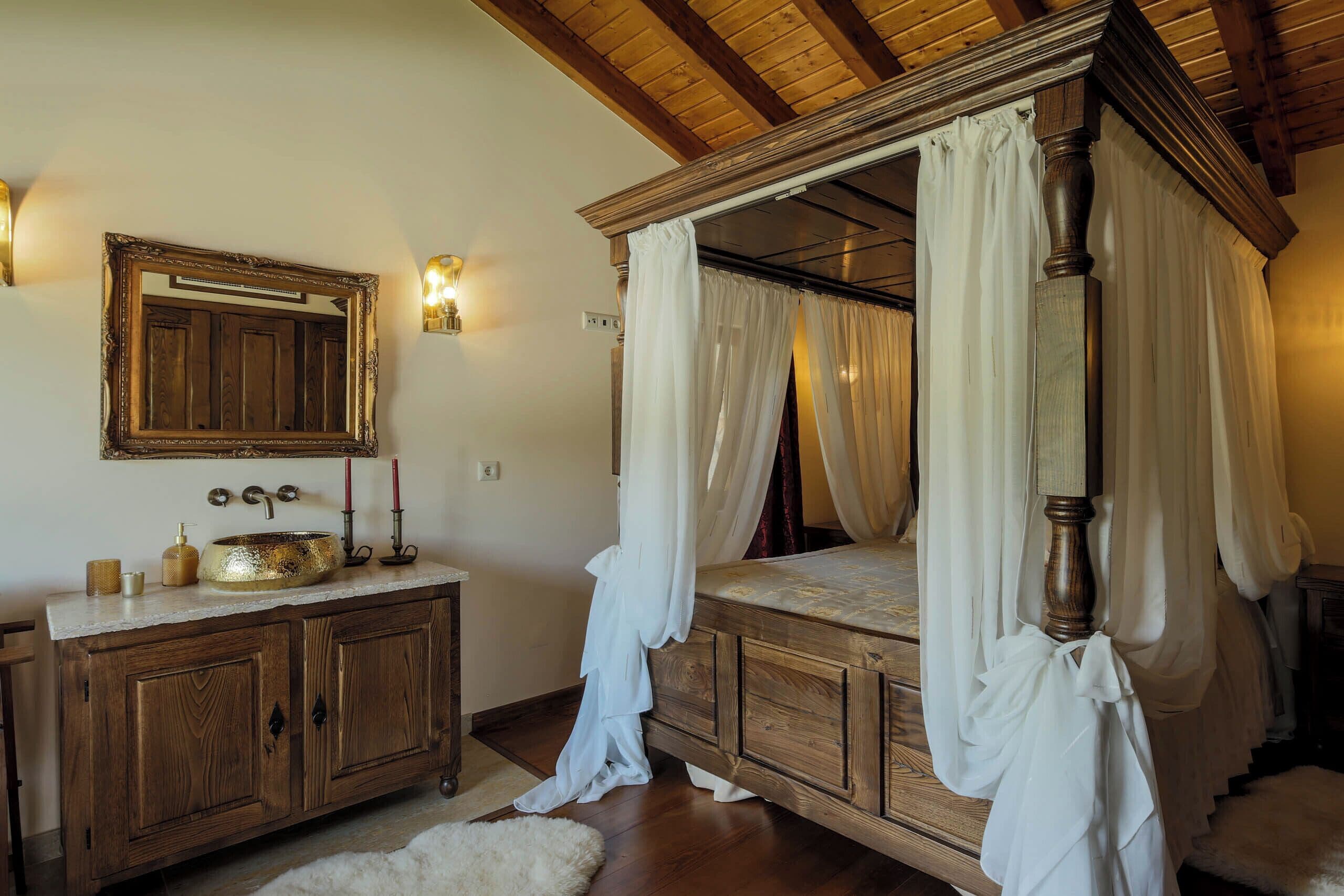 A bedroom with a four-poster bed, wooden cabinets, a vanity with a mirror, and a chandelier.