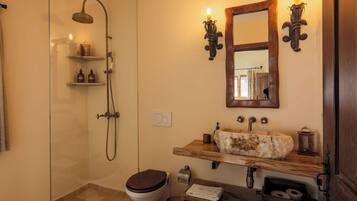 A bathroom with a glass-enclosed shower, a wooden vanity with a stone sink, and a mirror above the sink.
