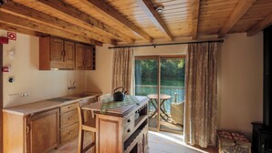 Une cuisine en bois dotée d’une grande fenêtre, un coin repas avec une table et des chaises, et une vue sur l’extérieur.