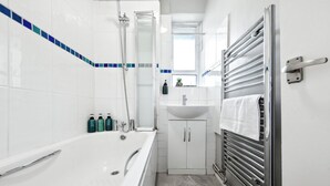 Un baño moderno con una bañera, ducha, lavabo y toallero.