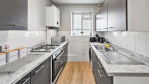 Una cocina moderna con armarios blancos, un microondas, una estufa a gas y un lavamanos.