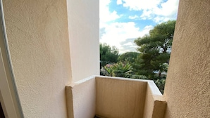 Un petit balcon fermé, d’où l’on peut admirer les arbres et un ciel nuageux.