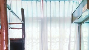 A small, compact room with a bunk bed, a desk, a chair, a window with sheer curtains, and a tiled floor. - Sinsiamresort (Klaeng)