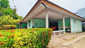 A building with a covered porch, green walls, and a bench. - Sinsiamresort (Klaeng)