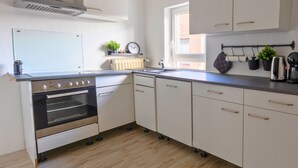 A modern kitchen with a built-in oven, white cabinets, and a window providing natural light.