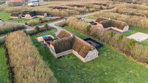Área rural com casas tradicionais de colmo, piscina e vista ampla da paisagem circundante.