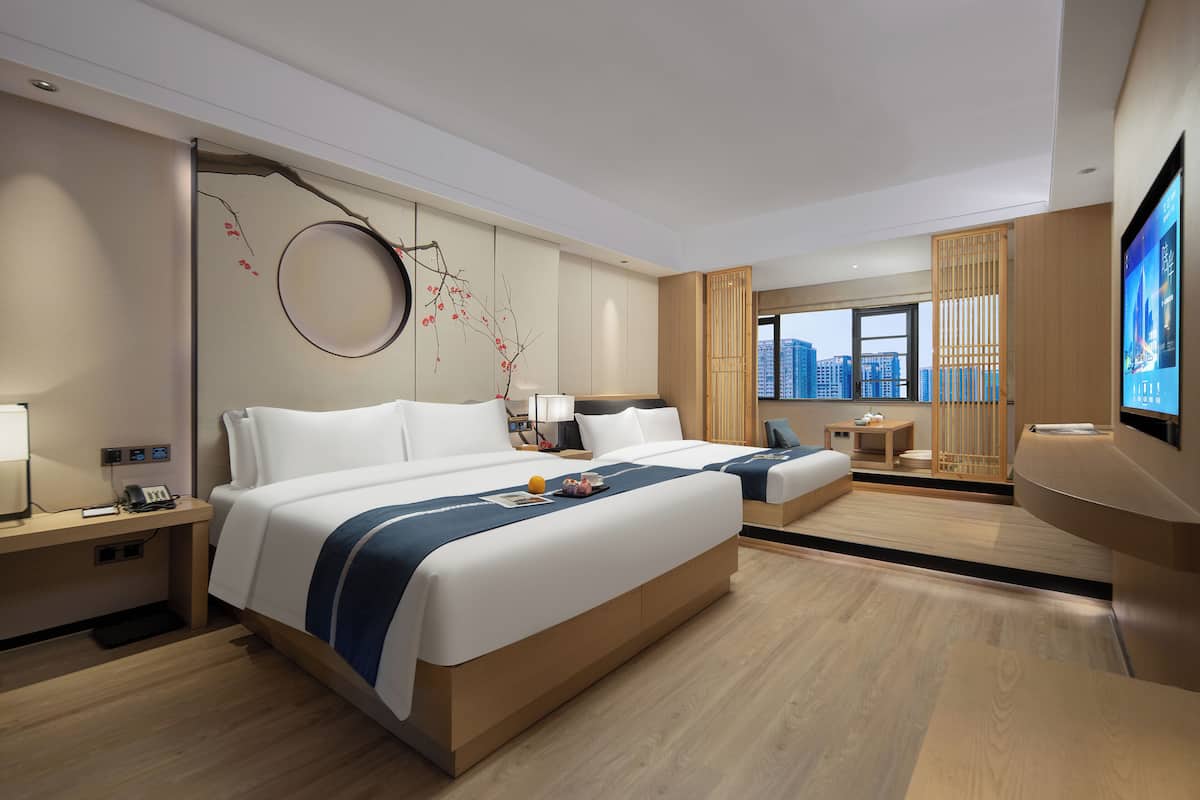 A modern hotel room with a large bed, bedside tables, a desk, and a TV.