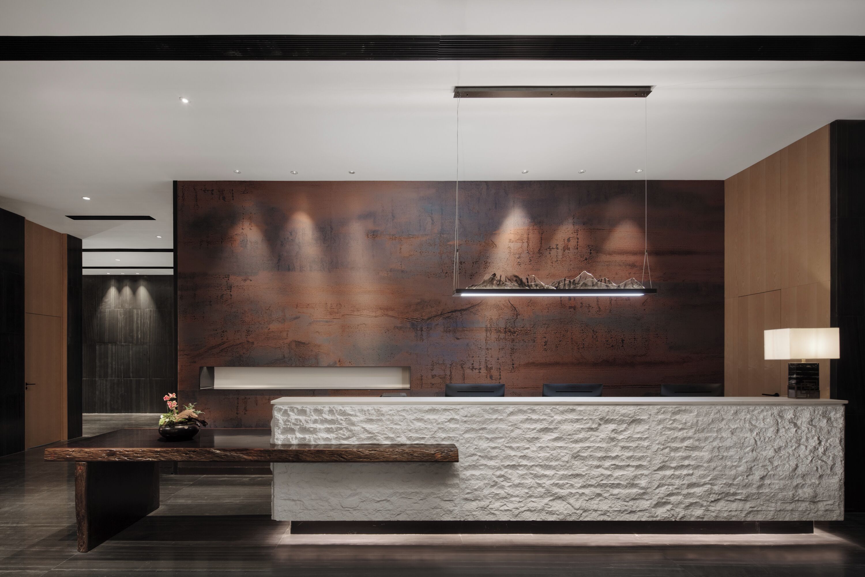 A modern reception area with a stone counter, wooden panel walls, and a minimalist design.