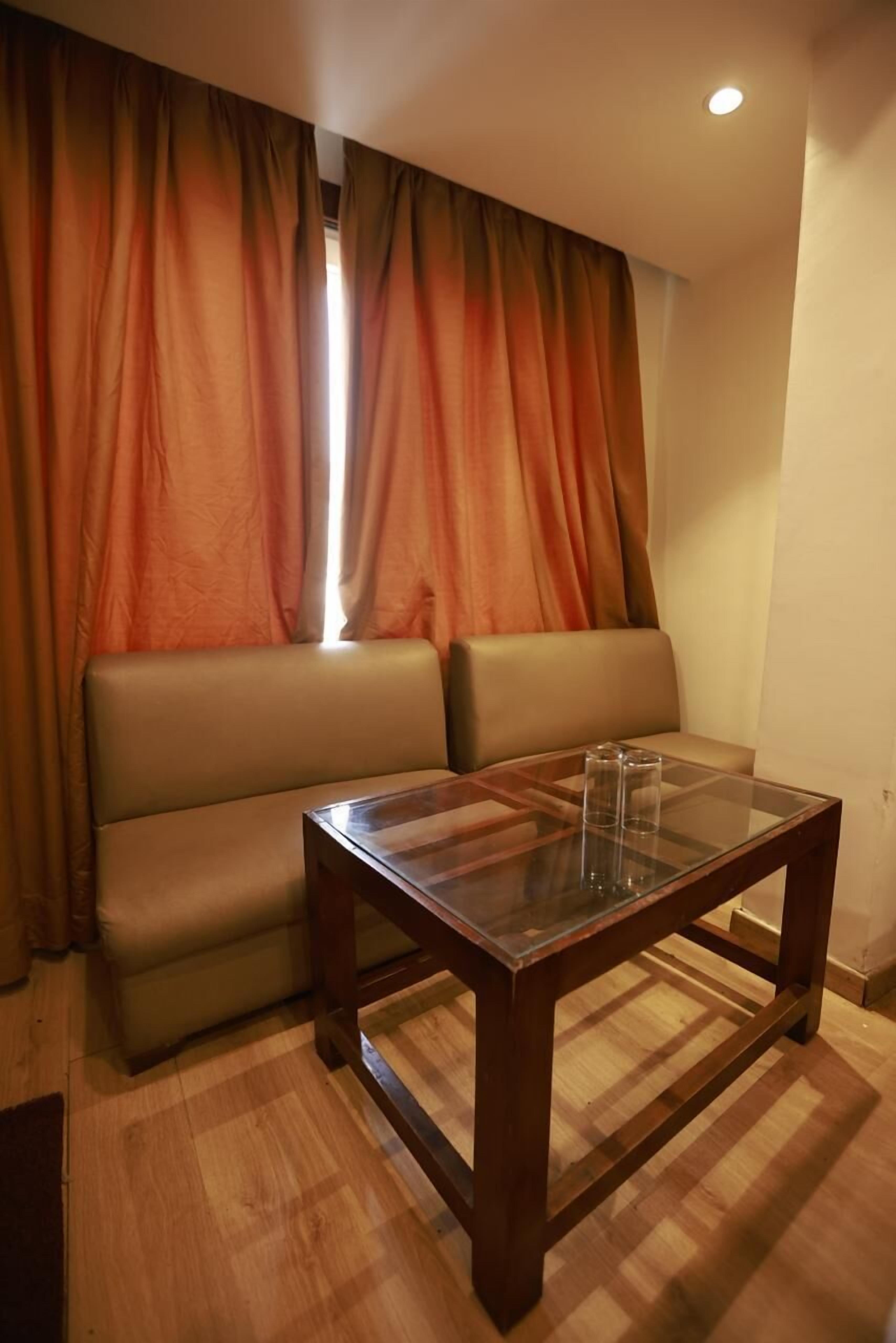 A room with a sofa, a glass-top table, and curtains.