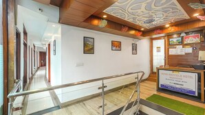 A hotel reception area with a glass railing, wooden ceiling, and framed pictures on the wall.