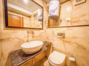 A bathroom with a marble sink, a mirror, a toilet, and a water heater.