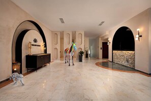 A spacious lobby with a marble floor, a black console, and a colorful horse statue.