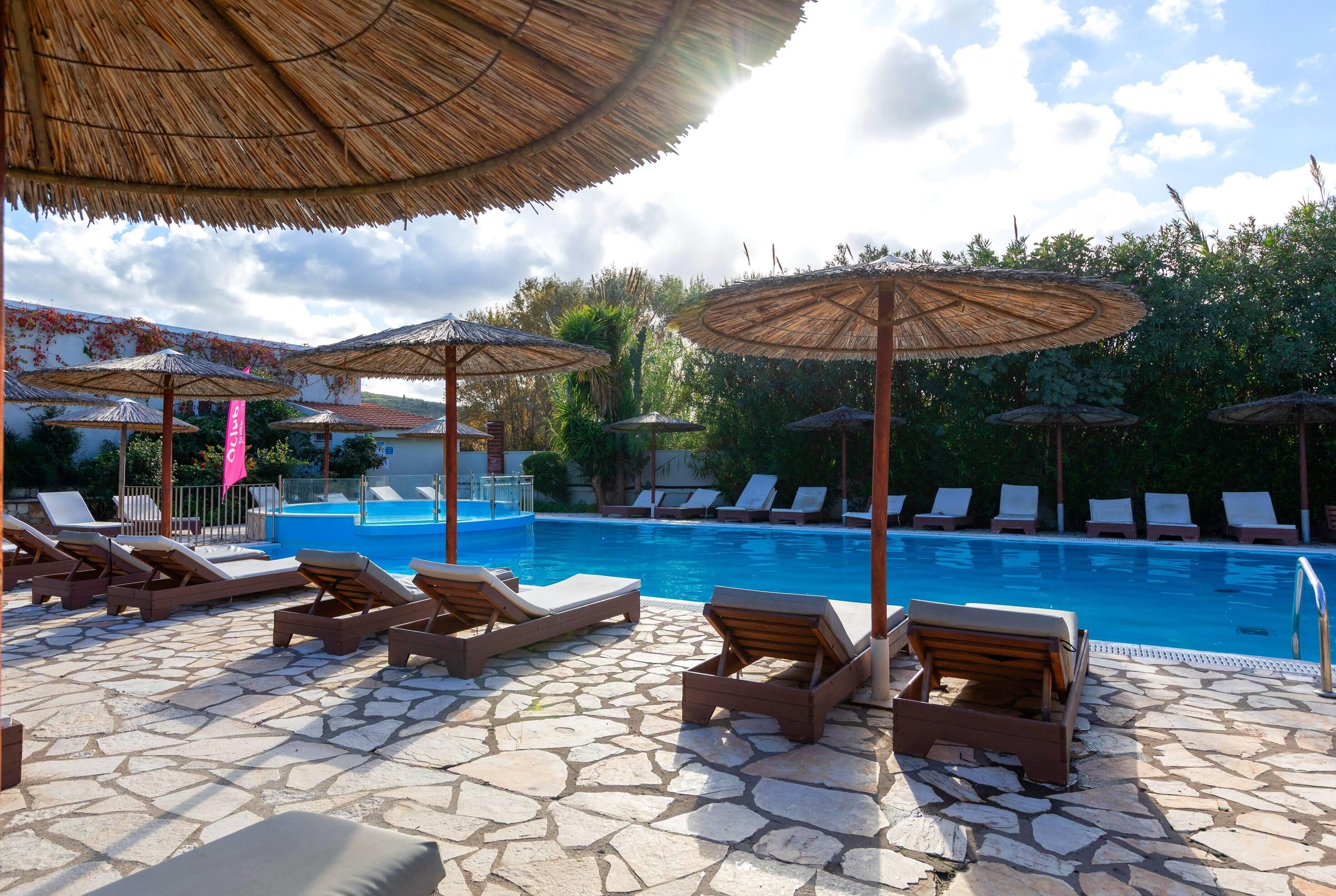A poolside area with lounge chairs and thatched umbrellas.