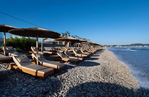 On the beach, black sand, sun loungers, beach umbrellas