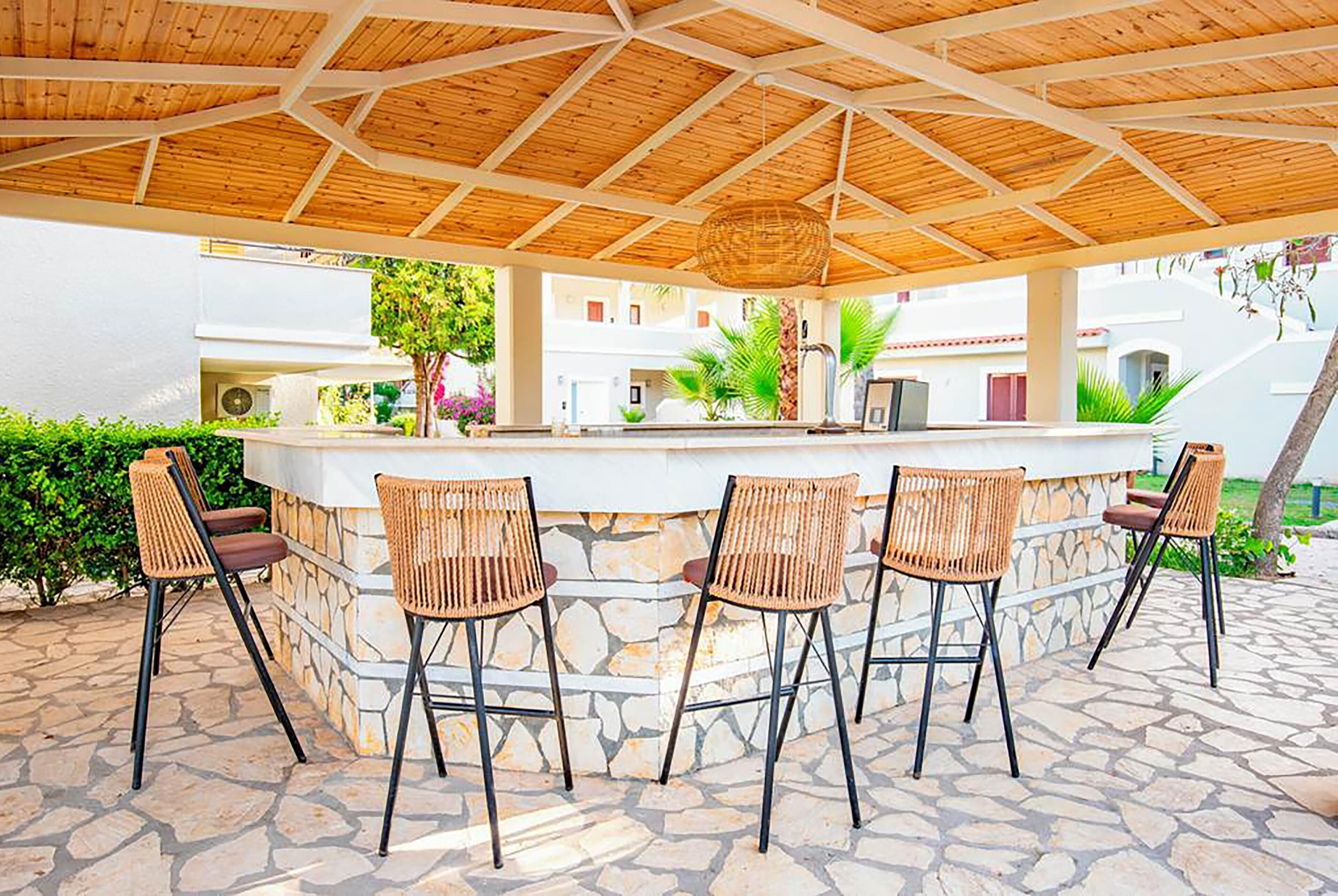 An outdoor bar area with a stone counter and wicker chairs.