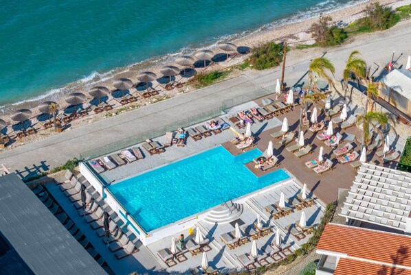 An aerial view of a resort with a swimming pool, sun loungers, umbrellas, and a beach area. - Wyndham Corfu Acharavi (Corfu)