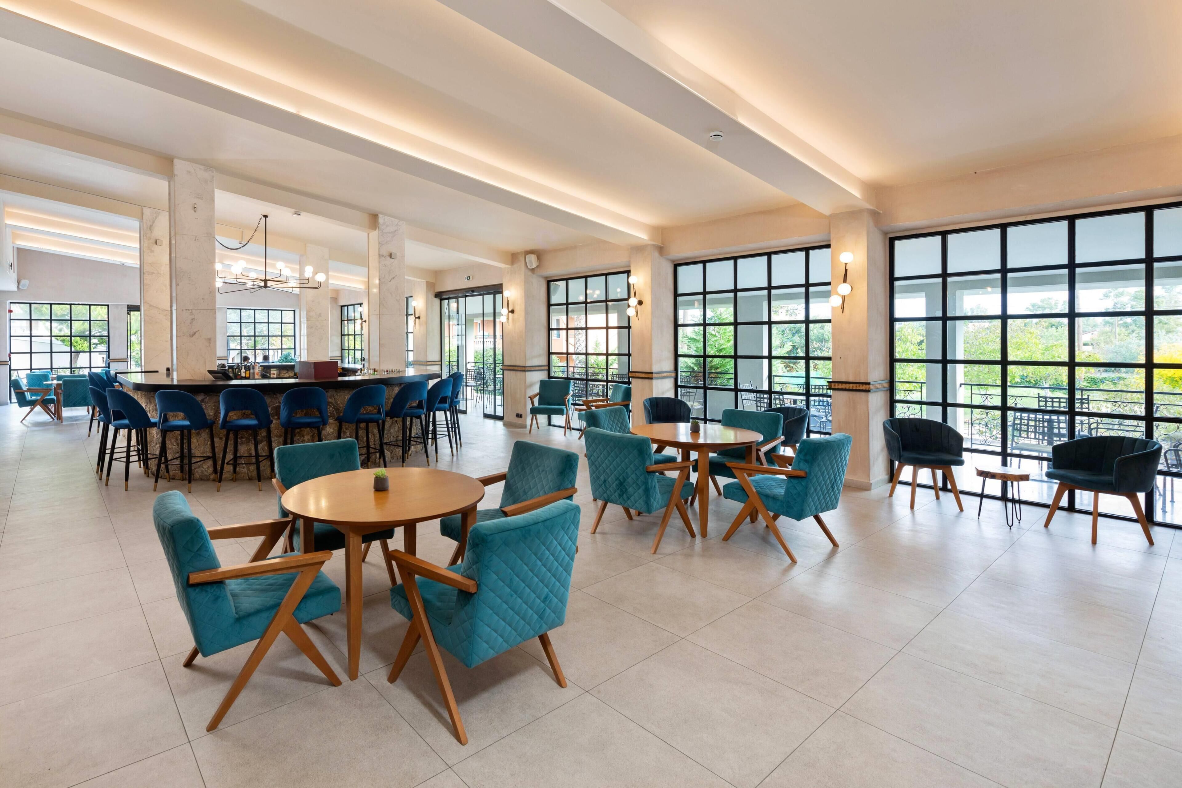 A spacious indoor area with multiple seating arrangements, large windows, and a bar area.