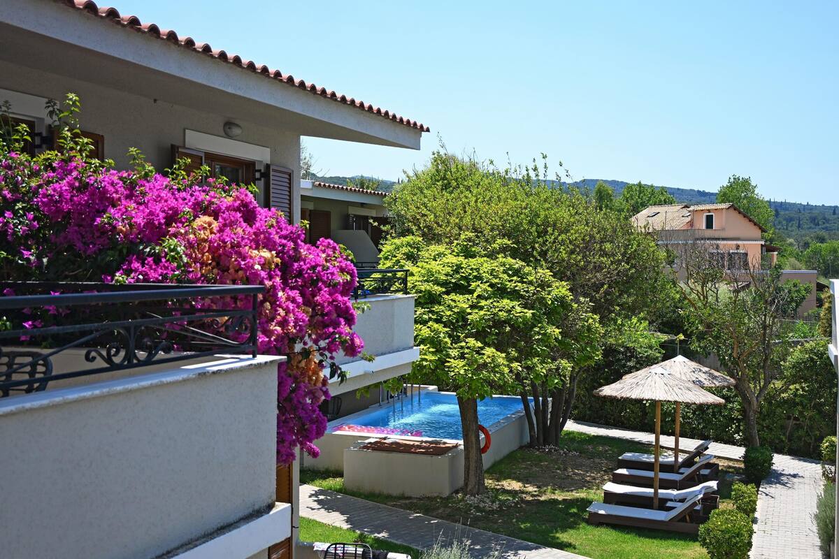 A pool area with a hot tub, a pergola, and a view of the surrounding landscape.